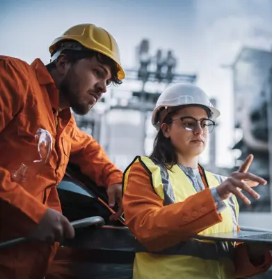 two engineers man and woman using laptop to work at power plant on night shift.