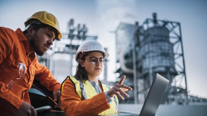 two engineers man and woman using laptop to work at power plant on night shift.