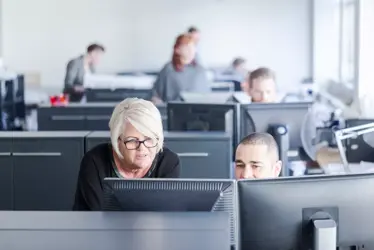 instructor working with adult student on desktop computer in learning center