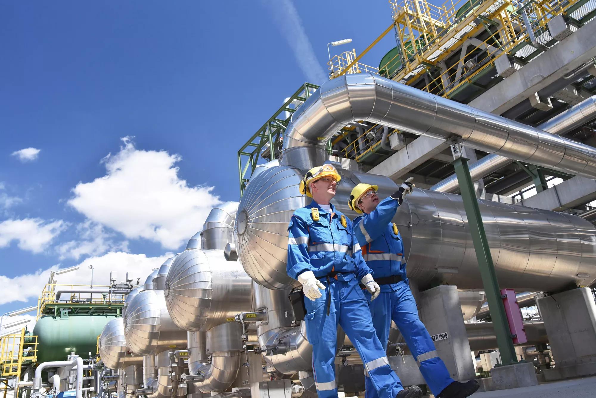 group of industrial workers in a refinery - oil processing equipment and machinery