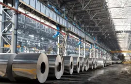 Long row of rolls of aluminum in production shop of plant.