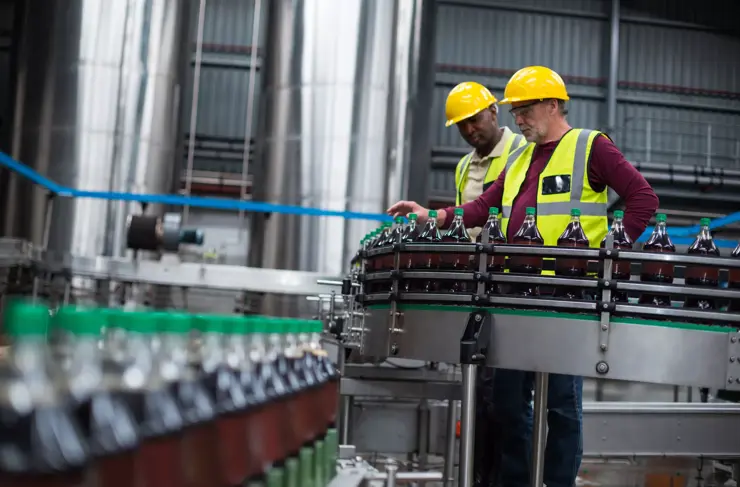 Gros plan de deux ouvriers surveillant des bouteilles de boissons fraîches dans une usine de production de boissons