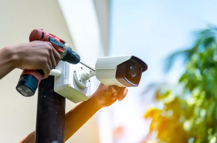 Closeup view, security tech installs pole-mounted CCTV camera