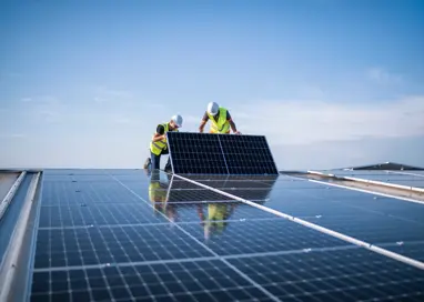 two engineers installing solar panels on roof.
